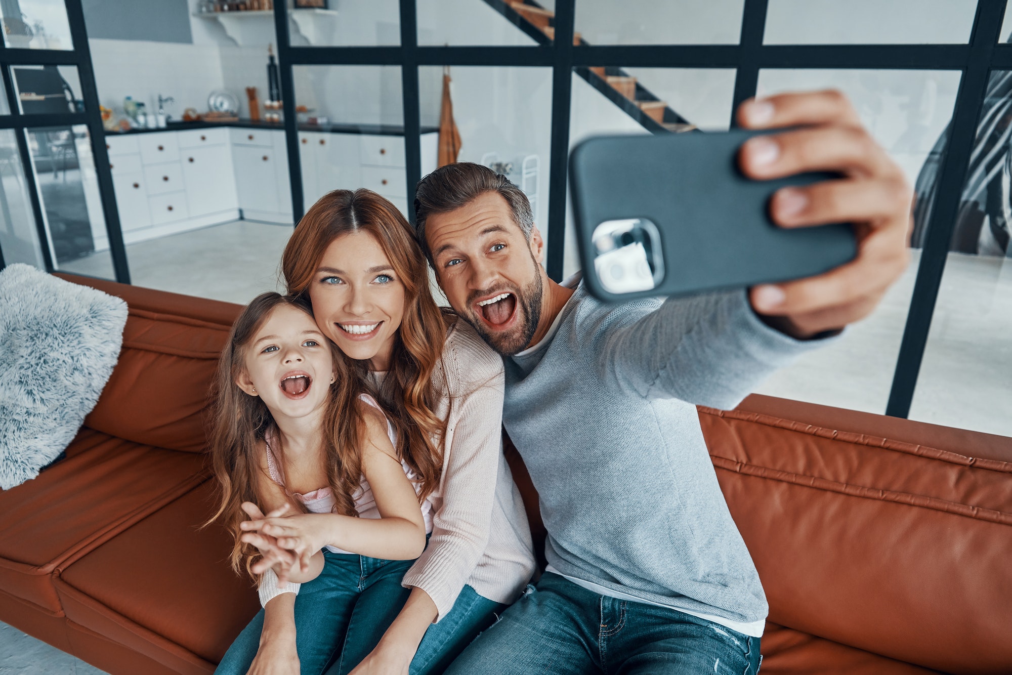 Playful young family smiling and making selfie while spending time at home